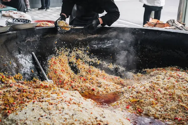 Erkek aşçı, pişmiş Özbek pilavını bir tabağa koyar. Geleneksel Doğu Arap pirinç mutfağı. Orta Asya Pilaf Merkezi Besh Qozon, Özbekistan, Taşkent