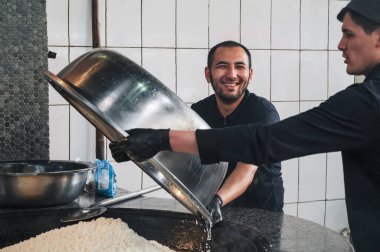 Mutlu erkek şefler, Orta Asya Pilaf Merkezi Besh Qozon 'daki bir restoranın mutfağında Özbek pilavı için pilav hazırlıyorlar. Taşkent, Özbekistan - 16 Nisan 2024