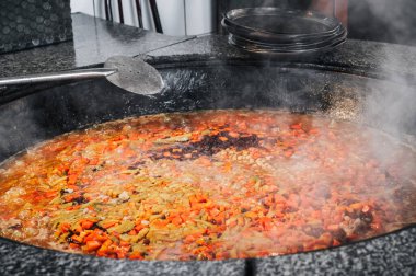 Özbekistan 'ın Taşkent kentindeki restoranın mutfağında geleneksel Özbek pilavı pişirmek için havuç, nohut ve kuru üzüm bir kazanda kaynatılır.