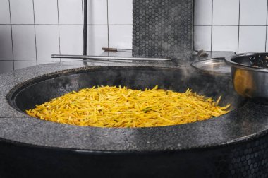 Özbekistan 'ın Taşkent kentindeki mutfakta Asyalı Özbek pilavı pişirmek için sarı havuçlar kazanda pişiriliyor