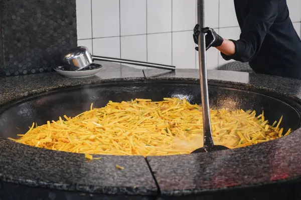 Stock image male cook stew yellow carrots in a cauldron for cooking traditional Uzbek pilaf in the kitchen at a restaurant in Uzbekistan