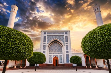 Özbekistan 'ın Taşkent kentindeki yeni beyaz Özbek İslami Mescid Camii' nin avlusunda yaz aylarında turuncu günbatımı gökyüzünün arka planında