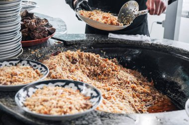 Özbekistan 'da bir restoranın mutfağında geleneksel Özbek pirinç pilavı pişiren erkek aşçı