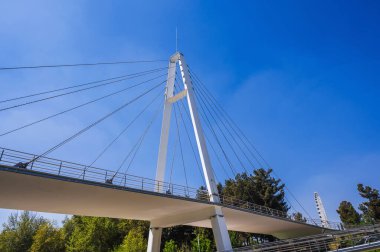 Özbekistan 'ın Taşkent kentindeki Anhor Park' ta mavi gökyüzünün arka planında modern bir kablo destekli köprü inşa edildi. Özbek yeni yaya asma köprüsü