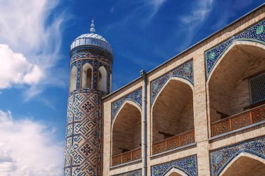 Taşkent Özbekistan 'daki Kukeldash medresesinin doğu desenli seramik fayanslarla süslenmiş tuğla duvarlar. Mavi gökyüzünün arka planında eski bir İslami medrese