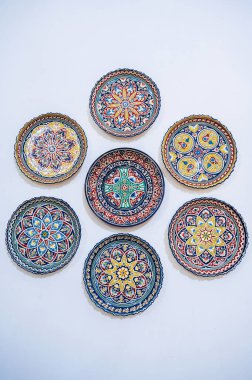 Özbek geleneksel seramik tabakları Özbekistan 'daki doğu hediyelik eşya dükkanının beyaz duvarına elle boyandı