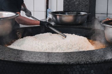 Özbekistan 'ın Taşkent kentindeki büyük bir restoranda geleneksel Asya Özbek pirinç pilavı pişiren adam.