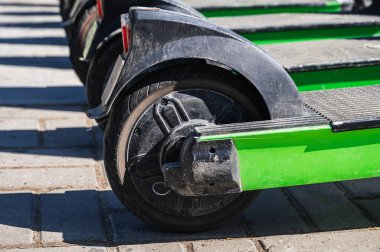 Yeşil elektrikli scooter 'ların tekerleri yazın şehrin kaldırımını kiralamak için sırada bekliyor.