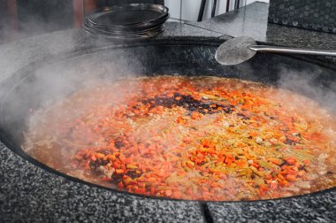 Özbekistan 'da bir restoranın mutfağında geleneksel Özbek pilavı pişirmek için havuç, nohut ve kuru üzüm bir kazanda kaynatılır.