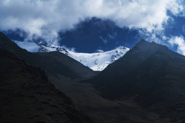 Arkasında kar olan buzulların dağ zirveleri bulutlu mavi bir gökyüzünün.
