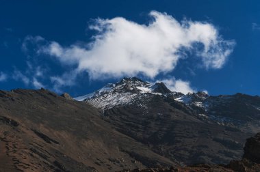 Arkasında kar olan buzulların dağ zirveleri bulutlu mavi bir gökyüzünün.