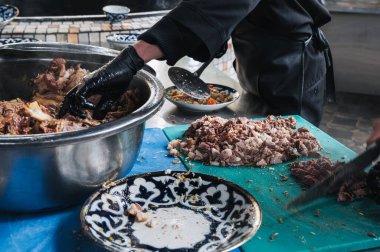 Özbekistan 'ın Taşkent kentindeki bir restoranda Özbek pilavı pişirmek için erkek şefler haşlanmış eti bıçakla kestiler