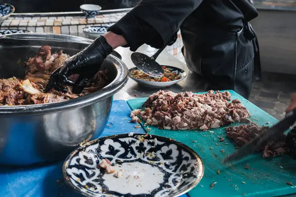 Stock image male hands chefs cut boiled beef meat with knives for cooking oriental Uzbek pilaf in kitchen at restaurant in Tashkent in Uzbekistan