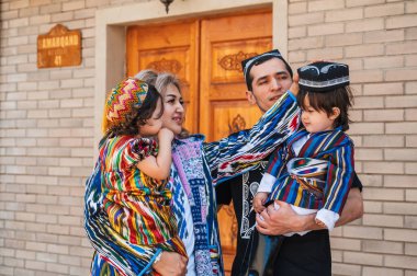 Şehirdeki sokakta geleneksel Özbek kostümlü mutlu Özbek ailesi. Taşkent, Özbekistan - 18 Nisan 2024