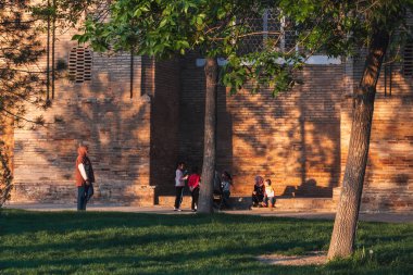 Özbek çocuklar baharda Barakhan medresesinin duvarlarının yanında yürüyüp oynuyorlar. Taşkent, Özbekistan - 17 Nisan 2024