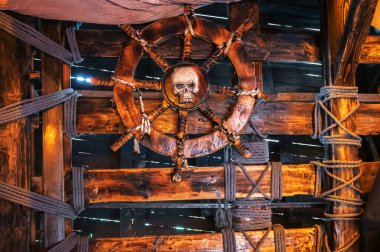 Eski bir ortaçağ korsan gemisinde kaptan kulübesinde kafatası olan tahta direksiyon.