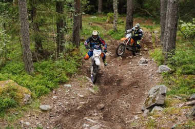 KARELİYA, RUSSIA REÜKLİK - CIRCA HAZİRAN 2022: Karelia 'da Ladoga Kupası 2022 off-road turnuvası. Enduro spor motosikletine binen motosikletli bir motosikletli ormandaki kayaların üzerinde motokros yarışı yapıyor.