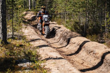 KARELİYA, RUSSIA REÜKLİK - CIRCA HAZİRAN 2022: Karelia 'da Ladoga Kupası 2022 off-road turnuvası. Motosikletli sporcu motosiklet sürücüsü ormanın tozlu yollarında motosiklet yarışı yapıyor.
