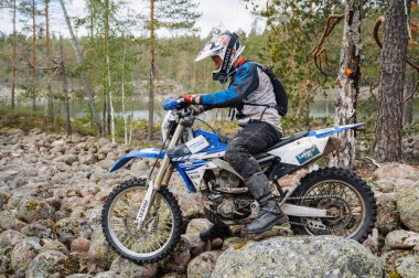 KARELİYA, RUSSIA REÜKLİK - CIRCA HAZİRAN 2022: Karelia 'da Ladoga Kupası 2022 off-road turnuvası. Bir motosiklet yarışçısı spor motokrosuyla kayaların üzerinden geçiyor.