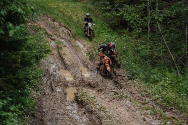 KARELİYA, RUSSIA REÜKLİK - CIRCA HAZİRAN 2022: Karelia 'da Ladoga Kupası 2022 off-road turnuvası. Dayanıklı spor motosikletli bir motosiklet yarışçısı orman yolunda çamurda kayıyor.