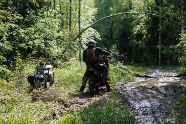 KARELİYA, RUSSIA REÜKLİK - CIRCA HAZİRAN 2022: Karelia 'da Ladoga Kupası 2022 off-road turnuvası. Enduro spor motosikletli motosiklet yarışçısı çamurlu orman yolunda motosiklet sürüyordu. Motokrosta su birikintileri vardı.