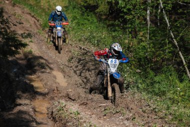 KARELİYA, RUSSIA REÜKLİK - CIRCA HAZİRAN 2022: Karelia 'da Ladoga Kupası 2022 off-road turnuvası. Dayanıklı spor motosikletli bir motosiklet yarışçısı orman yolunda çamurda kayıyor.