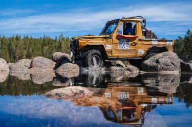 KARELIA, RUSSIA - CIRCA JUNE, 2022: Ladoga Gölü çevresindeki Off-road turnuvası Ladoga Kupası 2022. 4x4 Mercedes göl kıyısındaki kayalıklarda geziniyor.