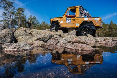 KARELIA, RUSSIA - CIRCA JUNE, 2022: Ladoga Gölü çevresindeki Off-road turnuvası Ladoga Kupası 2022. 4x4 Mercedes göl kıyısındaki kayalıklarda geziniyor.