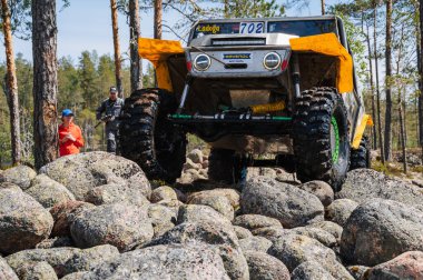 KARELIA, RUSSIA - CIRCA JUNE, 2022: Ladoga Gölü çevresindeki Off-road turnuvası Ladoga Kupası 2022. 4x4 Jeep arazi aracı ormanın ortasında kayaların üzerinden geçiyor.