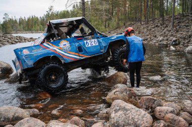 KARELIA, RUSSIA - CIRCA JUNE, 2022: Ladoga Gölü çevresindeki Off-road turnuvası Ladoga Kupası 2022. UAZ 4x4 arazi aracı, doğadaki bir gölde kayaların üzerinde bir yarışta yol alır.