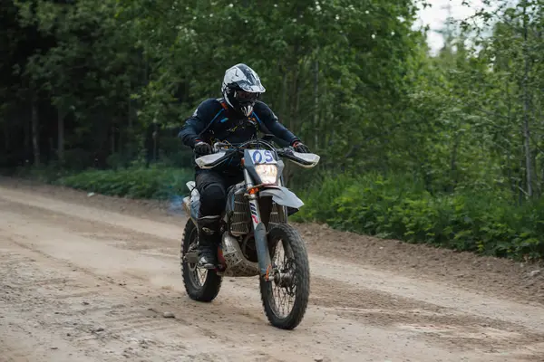 KARELİYA, RUSSIA REÜKLİK - CIRCA HAZİRAN 2022: Karelia 'da Ladoga Kupası 2022 off-road turnuvası. Bir motosiklet yarışçısı spor bir motosiklet üzerinde tozlu bir yolda motosiklet yarışına katılır.