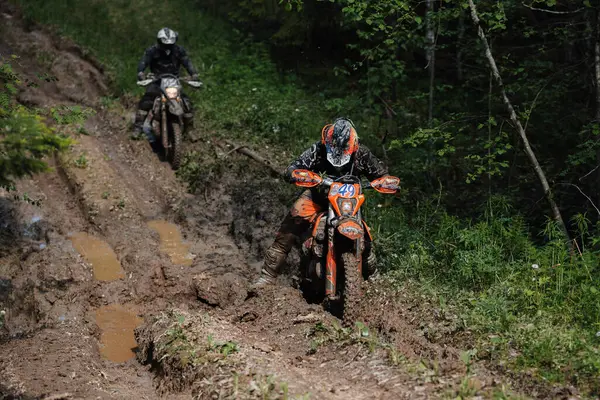 KARELİYA, RUSSIA REÜKLİK - CIRCA HAZİRAN 2022: Karelia 'da Ladoga Kupası 2022 off-road turnuvası. Dayanıklı spor motosikletli bir motosiklet yarışçısı orman yolunda çamurda kayıyor.