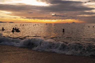 Sabahın köründe Nha Trang sahilinde yüzen insanların siluetleri. Nha Trang, Vietnam - 19 Temmuz 2024