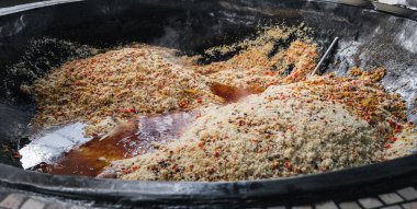 Özbekistan 'ın Taşkent kentindeki Orta Asya pilav merkezinde büyük bir kazanda baharat ve sebzeli geleneksel Özbek pirinç pilavı