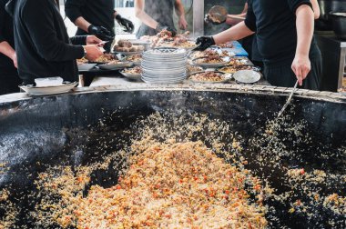 Erkek şefler restorandaki bir kazanda Özbek pilavı sebzeyle pişiriyor. Geleneksel Asya Özbek mutfağı. Orta Asya Pilaf Merkezi Besh Qozon, Özbekistan, Taşkent