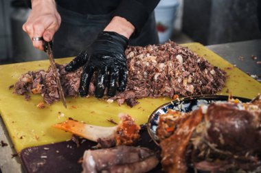 Özbekistan 'ın Taşkent kentindeki bir restoranda geleneksel Asyalı Özbek pilavını pişirmek için aşçı elleri bıçakla haşlanmış kuzu eti kesiyor.