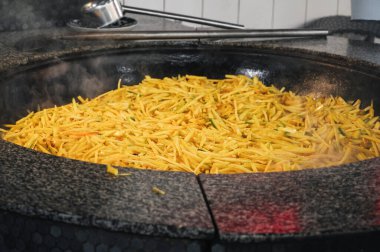 Sarı havuçlar Özbekistan 'ın Taşkent kentindeki bir restoranda geleneksel Asya Özbek pilavı pişirmek için bir kazanda pişiriliyor.