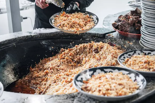 Geleneksel Arap Özbek pirinç pilavı pişiren bir erkek şefin elleri. Kazanda kuzu eti var. Orta Asya Pilaf Merkezi Besh Qozon, Özbekistan, Taşkent