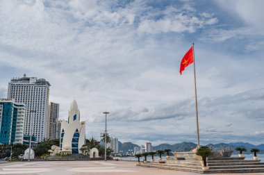 central square in Nha Trang city with the Lotus Tower and the flag of Vietnam on a cloudy morning in summer clipart