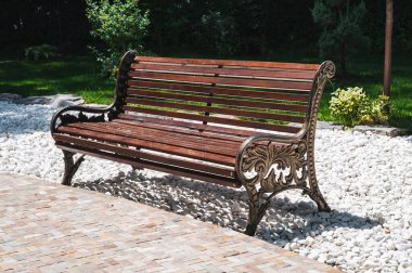 Şehir parkında ağaçların arkasında güzel bir ahşap tezgah..