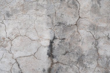 Üzerinde çizikler ve çatlaklar olan gri beton bir duvarın parçası.