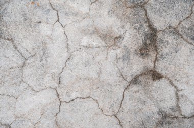 Üzerinde çizikler ve çatlaklar olan gri beton bir duvarın parçası.