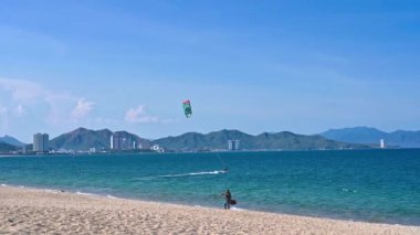 Uçurtma uçuran erkek uçurtma uçuruyor ve Asya 'daki Nha Trang' da dalgalara biniyor. Nha Trang, Vietnam - 23 Ağustos 2024