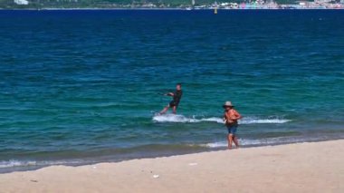 Erkek bir uçurtma ustası yazın Asya 'da Nha Trang' da denizdeki dalgalarda uçurtma uçuruyor. Nha Trang, Vietnam - 23 Ağustos 2024