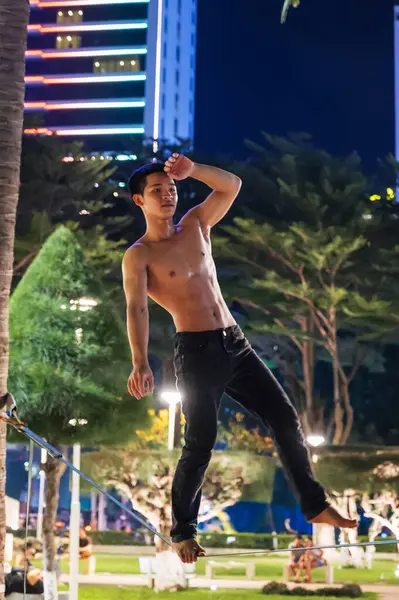 stock image young Asian male acrobat trains slackline standing on a tightrope in summer on a beach in Vietnam. Nha Trang, Vietnam - July 21, 2024