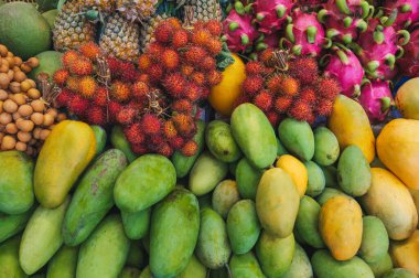 Vietnam 'da bir dükkanda tezgahın üzerinde çeşitli tropikal Asya meyveleri var. Vietnam sarısı ve yeşil mangoları, ejderha meyvesi ve rambutan