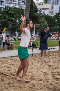 Halat eğitimi almış bir erkek akrobat yaz aylarında sahilde ipte yürür. Nha Trang, Vietnam - 25 Temmuz 2024
