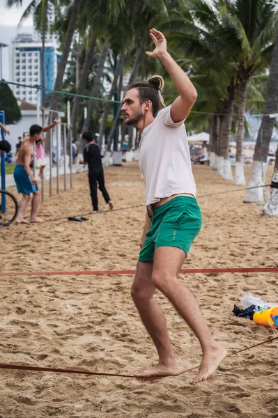 stock image A man in slackline training learns to walk a tightrope on the beach in summer. Nha Trang, Vietnam - July 25, 2024