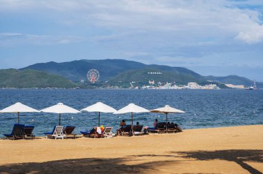 Plaj şemsiyeli kumsal ve Vietnam 'daki Nha Trang tatil beldesinde Vininci Adası' nda turistler.