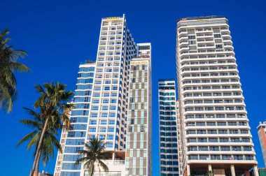 Yazın Vietnam 'da bir tatil köyünde mavi gökyüzüne karşı otellerin uzun modern gökdelenleri. Nha Trang, Vietnam - 13 Ağustos 2024